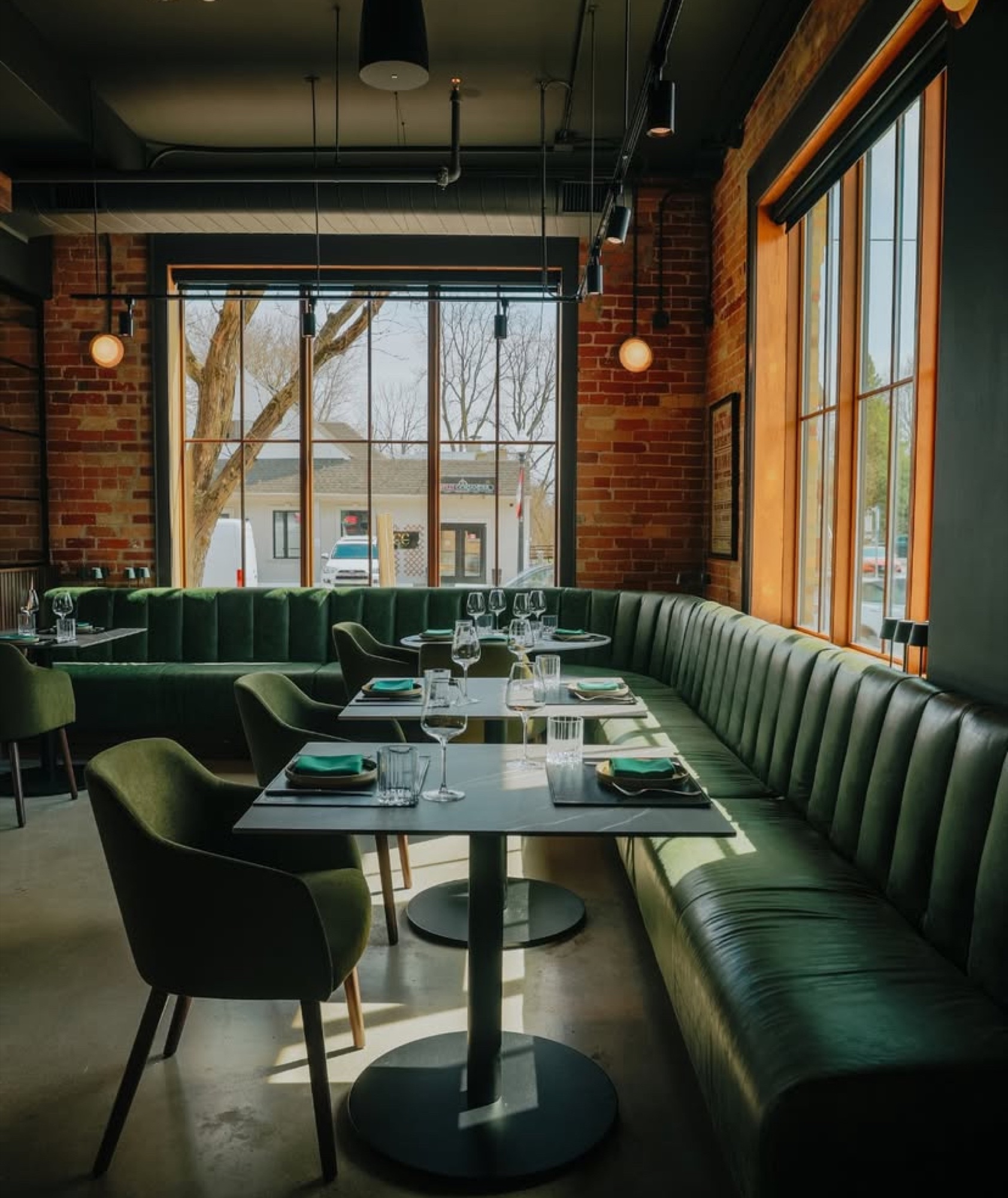 Restaurant dining room with green custom banquettes, tables and large windows